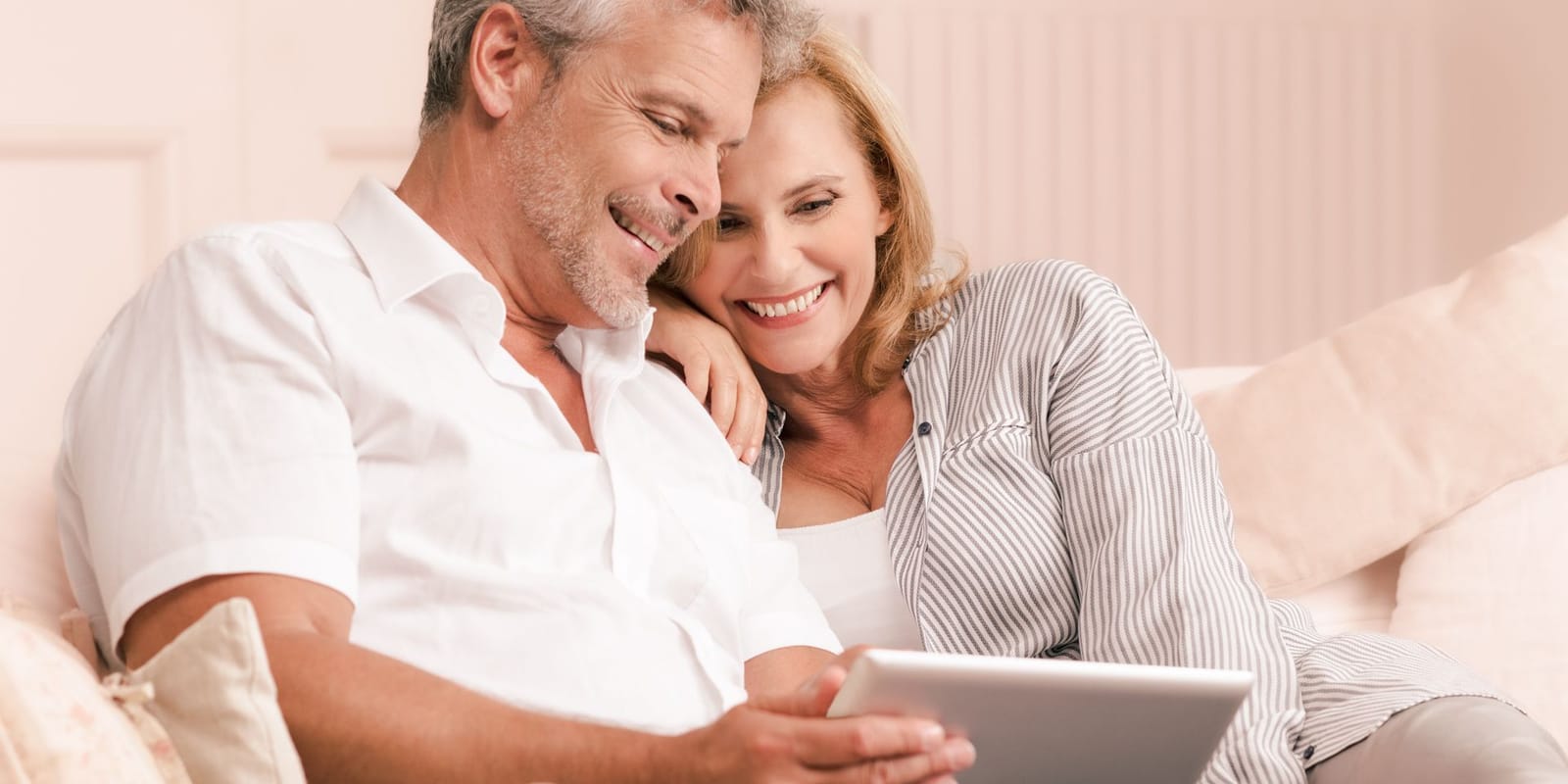 Couple smiling as they look at a tablet together at home